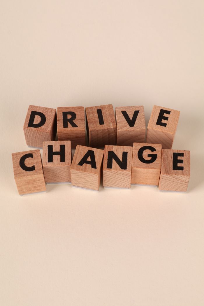 Wooden blocks arranged to spell 'Drive Change' on a neutral beige background, symbolizing transformation and progress.